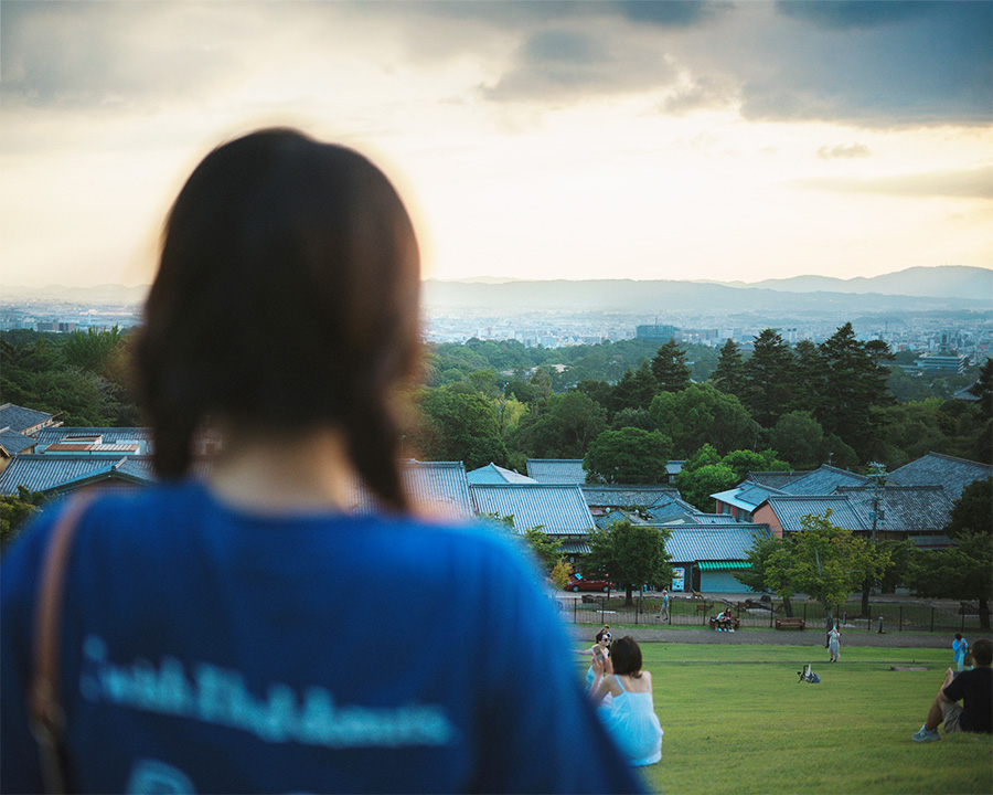 奈良で女性の一人旅が人気な理由：若草山で一人景色を眺める女性